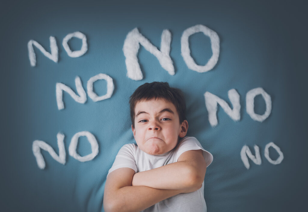 Bad boy on blue blanket background. Angry child with no words around.